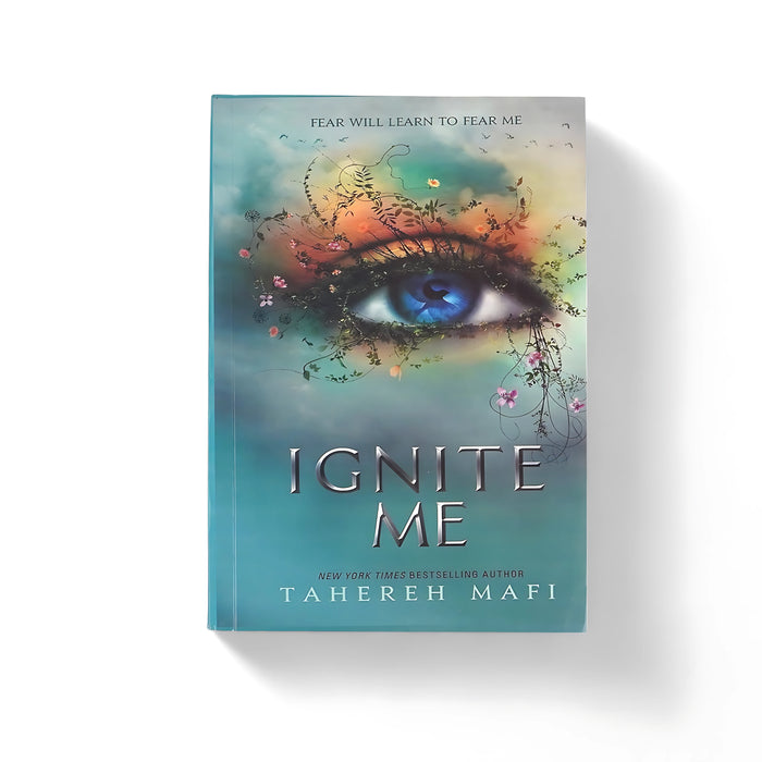 Cover of Ignite Me by Tahereh Mafi, featuring a vibrant blue eye surrounded by floral vines, symbolizing growth and transformation, set against a teal-colored background.