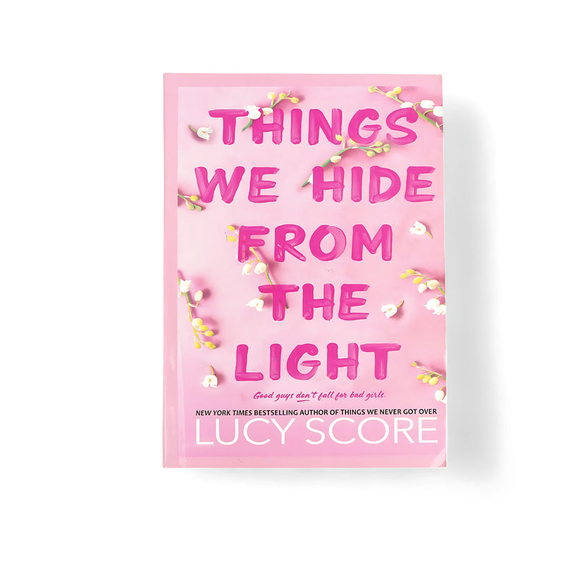 Cover of Things We Hide From the Light by Lucy Score, featuring a pink background with white flowers, symbolizing emotional healing and renewal.






